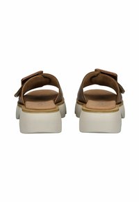 Sandales en cuir marron avec une large lanière et une semelle épaisse de couleur claire. L'intérieur présente un coussin lisse de couleur tan. Peu de matériel visible.