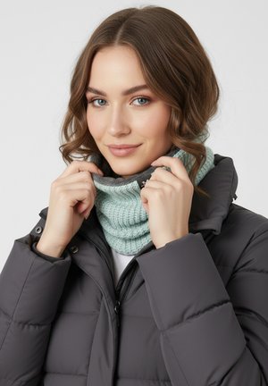 Hellgrüner gestrickter Kragenpullover mit geripptem Muster, getragen unter einer dunkelgrauen Steppjacke. Glattes Material und enge Passform.