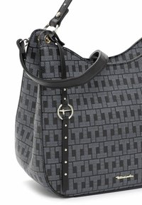 Sac à main à motifs noir et gris avec un design géométrique en "T" répétitif, bandoulière en cuir noir, détail en anneau argenté et petite plaque logo dorée.