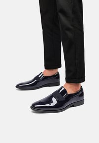 Zapatos de charol navy con un diseño elegante, que presentan una banda elástica en la parte superior y un tacón bajo y cuadrado para mayor estabilidad.