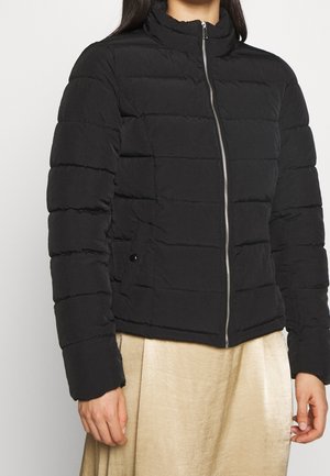 Doudoune noire avec col haut, design matelassé horizontal, zip frontal et poches latérales. Texture douce avec une finition mate.