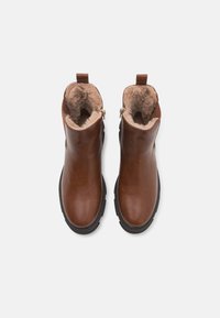 Bottines en cuir marron avec doublure en fausse fourrure, bout rond, fermetures éclair latérales, semelle en caoutchouc noir et languettes à l'arrière.
