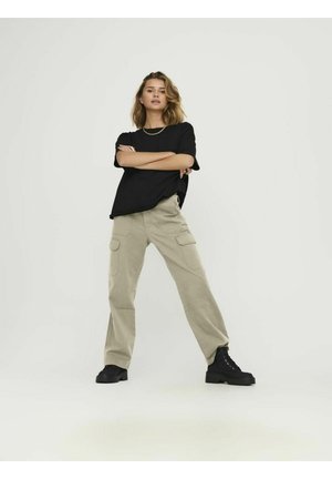 Schwarzes T-Shirt mit kurzen Ärmeln, kombiniert mit beigefarbenen Cargo-Hosen mit Seitentaschen; Modell trägt schwarze klobige Stiefel vor einem schlichten Hintergrund.