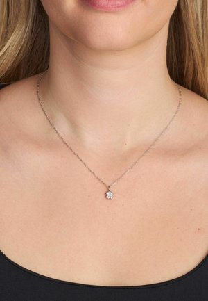 Collana con catena d'argento e ciondolo a forma di fiore con una gemma centrale e altre pietre più piccole, appesa elegantemente all'altezza del collo.