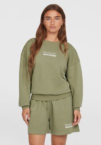 Maglione verde oliva e set di pantaloni corti abbinati; maglione dal taglio loose e con polsini a coste, presenta "The Future Surf Society" ricamato in bianco.