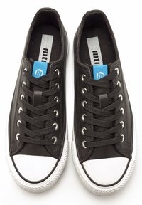 Zapatillas negras con punteras de goma blanca, que cuentan con cordones negros, ojetes de metal y una etiqueta de acento azul. Material suave y interior textil.
