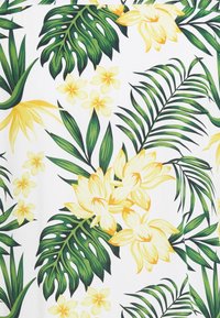 Tropiikkikangas, jossa on suuria vihreitä lehtiä, keltaisia kukkia ja pienempiä kukkaaccentteja valkoisella taustalla. Eroava kasvi-ihanne.