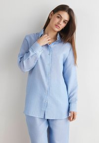 Lichtblauw gestreepte button-up shirt met een kraag en lange mouwen, gemaakt van textuurstof. Bevat witte knopen en heeft een relaxte pasvorm.