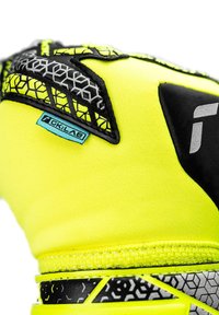 Guanto giallo neon con accenti neri, caratterizzato da un motivo testurizzato e un design esagonale. Include un'etichetta blu con il nome del marchio.