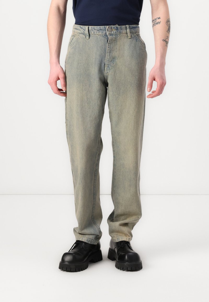 Lys blå denimjeans med avslappet passform, med framlommer, beltehemper og en falmet tekstur. Kombinert med svarte klumpete sko.