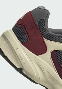 Zapatilla con parte superior de malla gris, acentos de ante burdeos, media suela de goma crema y suela exterior texturizada negra. Presenta la marca Cloudfoam.