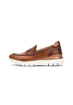 Zapato marrón de cuero sin cordones con un acabado suave, que cuenta con una suela de goma blanca y un detalle en bronce en el talón. Diseño simple y aerodinámico.