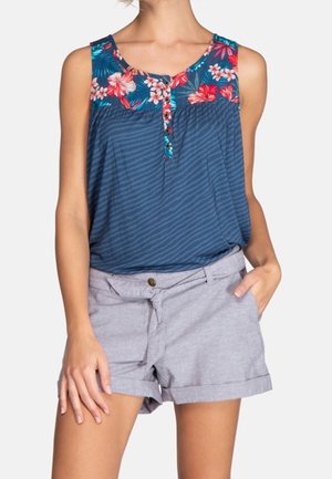 Bezrękawnik w kwiatowy wzór z materiału w niebiesko-białe paski, z guzikiem z przodu. Połączony z jasnoszarymi, podwiniętymi szortami.