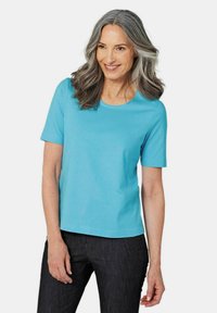 Turquoisekleurig T-shirt met korte mouwen en een ronde halslijn, gemaakt van zachte stof, gecombineerd met donkere jeans, met een relaxed fit en een gladde textuur.