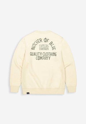 Creme kleurige sweatshirt met een gestructureerde afwerking, met op de achterkant donkergroene tekst: "BUTCHER OF BLUE CUTTERS EIGHTEEN QUALITY CLOTHING COMPANY."