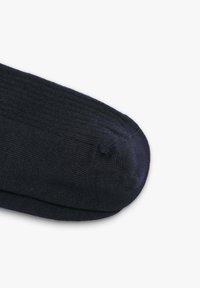 Marineblauwe sok gemaakt van een gladde brei-fabricage. Heeft een versterkte teen en een naadloos ontwerp met ribbeltextuur aan de bovenkant.