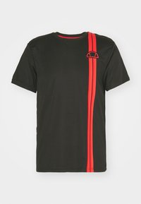 Camiseta negra de manga corta con una raya vertical roja y un logo en el lado izquierdo. El tejido parece suave y elástico.