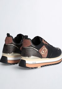 Sneaker neri e marroni con tomaia testurizzata, dettagli dorati, colletto imbottito e suola intermedia bianca. Suola in gomma spessa per una buona aderenza.