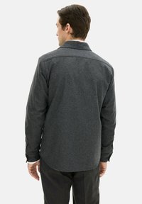 Gray, wool-blend, long-sleeve shirt with a pointed collar and rounded hem; features subtle texture and buttoned cuffs, viewed from the back.