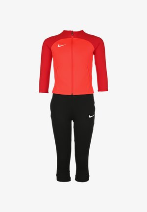 Czerwona kurtka zapinana na zamek z rękawami do łokcia i czarne spodnie typu crop, obie wykonane z elastycznego materiału, z białymi detalami logo Nike.