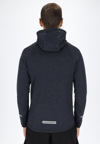 Dark gray hooded sweatshirt made of textured fabric. Features a logo at the back, thumbholes on sleeves, and a fitted design.