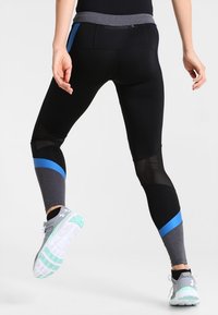 Czarne legginsy sportowe z niebieskimi i szarymi akcentami, siateczkowymi panelami, średnim stanem i kieszenią na zamek z tyłu.