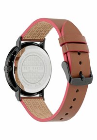 Ted Baker laikrodis su juodu nerūdijančio plieno korpusu, rudos odos dirželiu su rožiniais akcentais ir struktūrizuota smėlio spalvos vidine dalimi. Atsparus vandeniui iki 50 m.