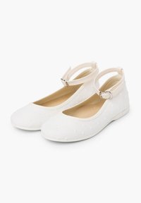 Ballerine bianche con finitura liscia, dotate di punta rotonda, cinturino alla caviglia e motivo a pois sulla parte superiore. Morbido rivestimento interno.