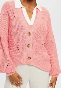 Cardigan rose en tricot avec col en V, trois boutons en bois et poignets côtelés. Présente un design en tricot ajouré et une couche supérieure en dessous.