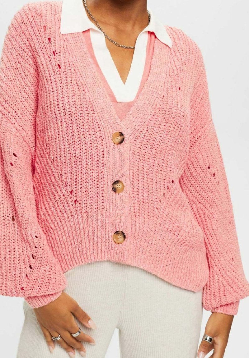 Cardigan rose en tricot avec col en V, trois boutons en bois et poignets côtelés. Présente un design en tricot ajouré et une couche supérieure en dessous.