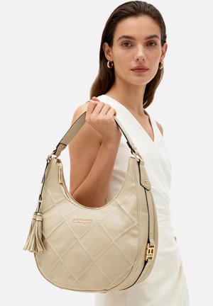 Borsa hobo in pelle trapuntata beige con accenti dorati, nappina e tracolla removibile. Presenta un design spazioso e una texture liscia.