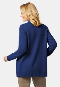 Pull en bleu marine à manches longues, avec des poignets et un ourlet côtelés. Fabriqué dans un tissu doux, il présente une coupe décontractée, légèrement surdimensionnée.