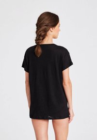 Must have pehmeast kangast must oversized t-särk, lühikeste varrukatega, ümmarguse kaelusega ja vaba lõikega, mille tagumine osa on veidi pikem.