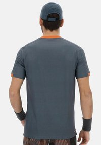 Camiseta atlética gris de manga corta, con acentos naranjas en el collar y las mangas, textura suave y un diseño transpirable.