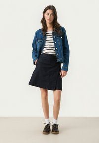 Veste en denim, chemise rayée, jupe portefeuille marine et chaussures sombres avec des chaussettes blanches. Présente un design décontracté, diverses textures et des lignes épurées.
