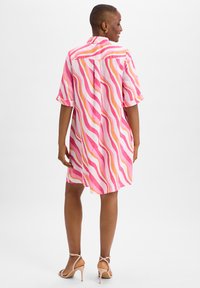 Kurzärmliges Kleid aus leichtem Stoff mit wellenförmigen Streifen in Pink, Orange und Weiß. Knopfleiste auf der Rückseite, lässige Passform, knielang.