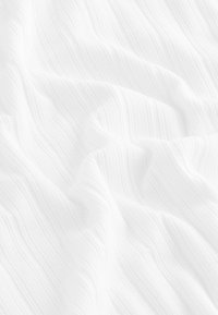 Texturiertes weißes Gewebe mit wellenförmigen Linien und subtilen Rillen, das ein weiches, fließendes Erscheinungsbild und eine glatte Oberfläche zeigt.