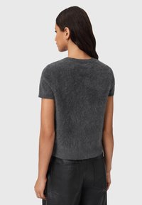 Kortærmet, fuzzy grå sweater med rund halsudskæring, båret med sorte læderbukser. Blød tekstur med en cropped design.