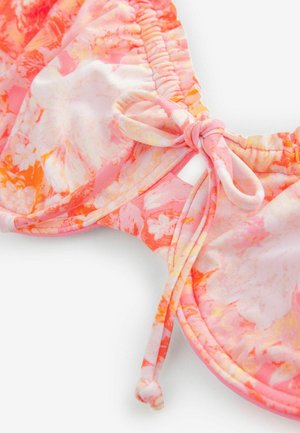 Kwiatowy staniczek bikini w kolorach różowym, pomarańczowym i białym, z marszczonymi brzegami i detalem w postaci kokardki. Gładka tkanina z żywym wzorem.
