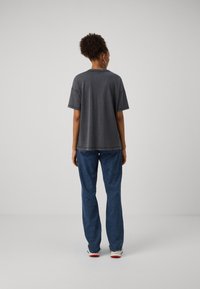 Graues, übergroßes T-Shirt mit kurzen Ärmeln, weichem Material und Rundhalsausschnitt, kombiniert mit lockeren blauen Jeans. Einfaches, lässiges Design.