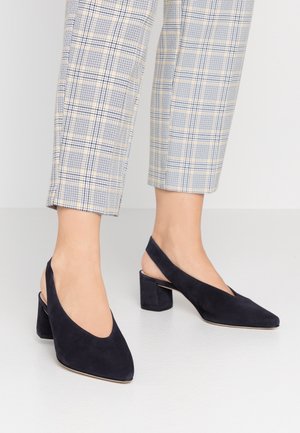 Granatowe zamszowe sandały na obcasie typu slingback z szpiczastym noskiem i średnim szerokim obcasem; charakteryzują się wycięciem w kształcie litery V oraz gładką fakturą.