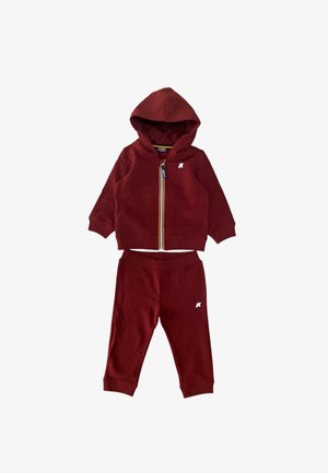 Completo in felpa rossa con cappuccio e pantaloni, caratterizzato da una chiusura con zip, cappuccio, polsini a coste e un piccolo logo sul petto e sulla gamba.