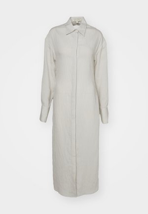 Ανοιχτό μπεζ μακρύ φόρεμα φτιαγμένο από υφασμάτινη υφή, με κλασικό γιακά, κλείσιμο με κουμπιά, μακρύ μανίκι και πλαϊνές τσέπες.