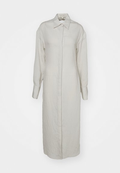 Ανοιχτό μπεζ μακρύ φόρεμα φτιαγμένο από υφασμάτινη υφή, με κλασικό γιακά, κλείσιμο με κουμπιά, μακρύ μανίκι και πλαϊνές τσέπες.