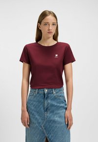 Burgundy cotton t-shirt with a round neckline, short sleeves, and a white heart graphic. Paired with a light blue denim skirt featuring a slit.