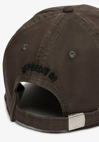 Gorra de algodón marrón con el logo bordado "SUPERDRY CO", un cierre de metal y un diseño clásico de visera curva con orificios de ventilación.