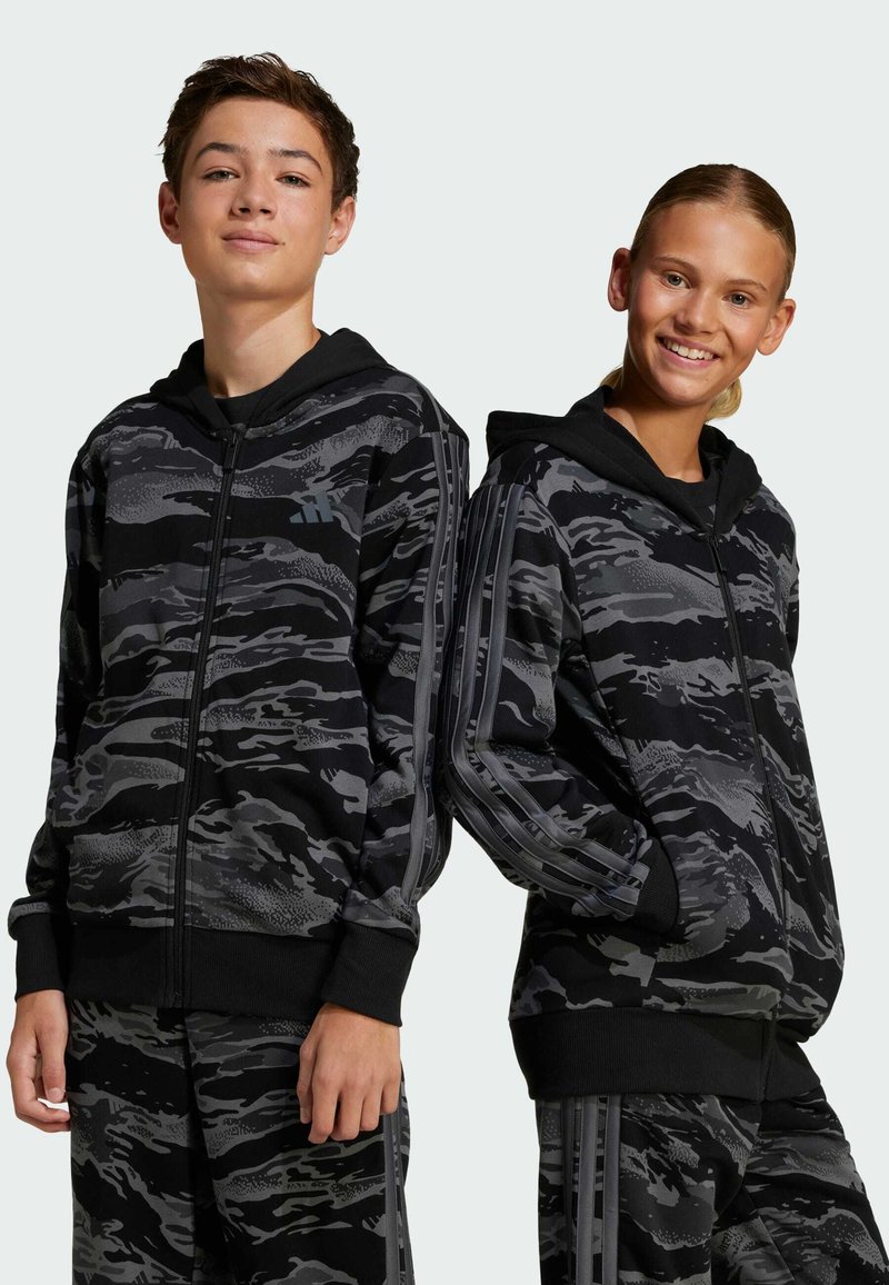 Sweatshirts zippés à capuche en camouflage noir et gris avec un tissu texturé, présentant des accents noirs et des rayures le long des manches.