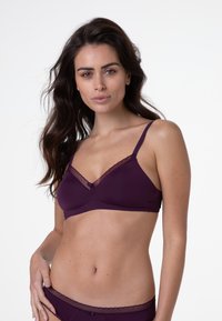 Senza fili bordeaux con rifiniture in pizzo trasparente, spalline regolabili e un piccolo fiocco al centro; tessuto liscio ed elastico.