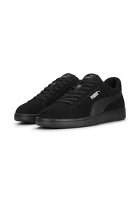 Sneakers neri in suede con finitura testurizzata, punta rotonda, design con lacci e suola in gomma nera. Presentano un logo Puma bianco sul lato.