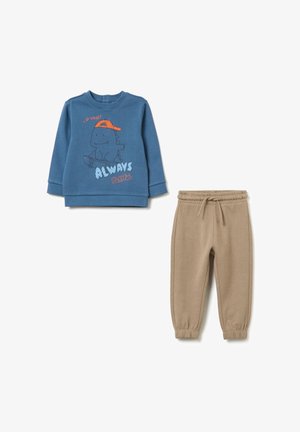Blauwe sweater met dinosaurustekening en de tekst "Altijd Speels", gecombineerd met beige joggingbroeken met een elastische tailleband.